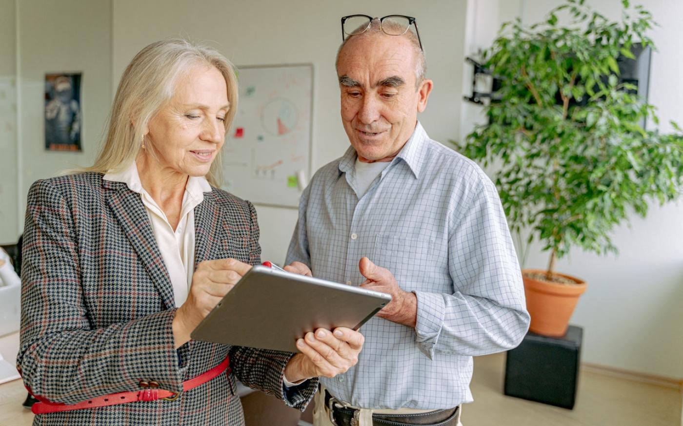 Two older businesspeople looking at a tablet screen
