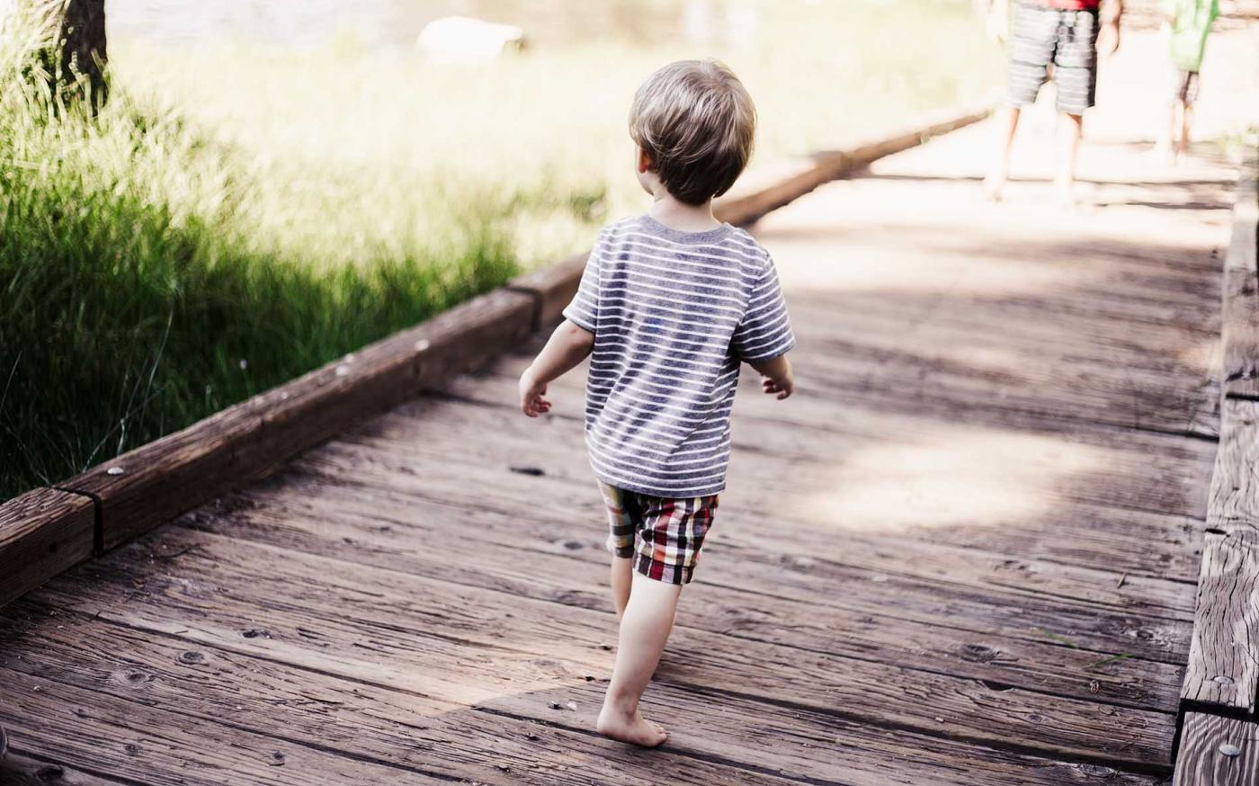 Child running on wooden bridge.