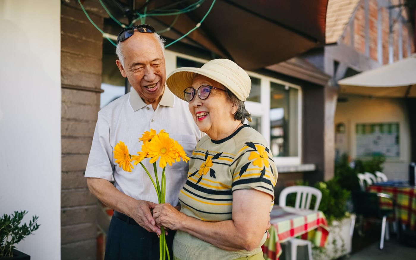 Happy elderly couple holding yellow flowers